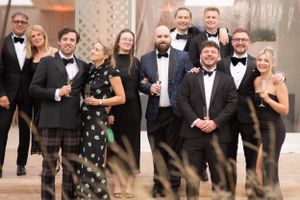 A formal group in black tie attire and evening wear poses together at an elegant event.