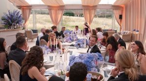 Guests seated at elegant tables with pink draping and purple decor during a formal dining event.