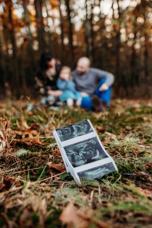 Maternity woman with family with ultrasound in front pregnancy announcement. Captured by Maryland maternity Photographer Mallory Bramlett.