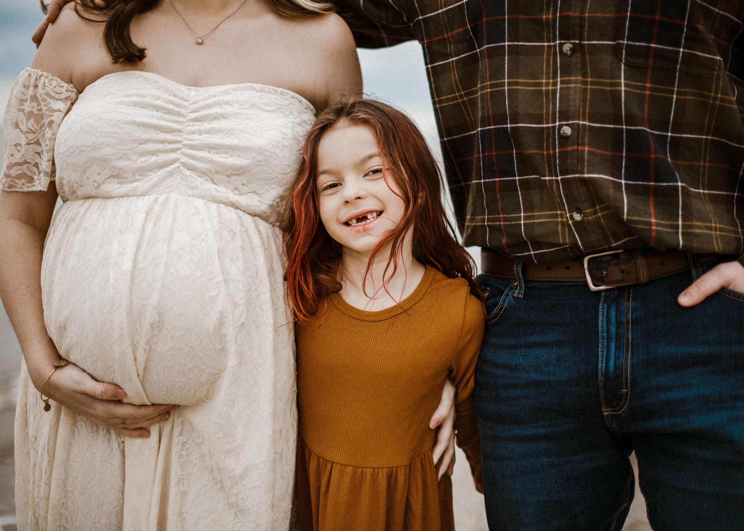 Maternity woman with family on beach for maternity portraits. Captured by southern Maryland  maternity Photographer Mallory Bramlett.