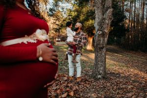 Maternity woman with family in background for maternity pictures. Captured by southern Maryland  maternity Photographer Mallory Bramlett.