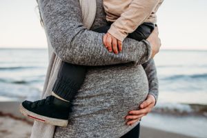 Maternity woman holding toddler on belly for maternity photoshoot. Captured by Maryland maternity Photographer Mallory Bramlett.