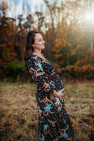 Maternity woman holding belly in field for maternity portraits. Captured by Maryland Photographer Mallory Bramlett.