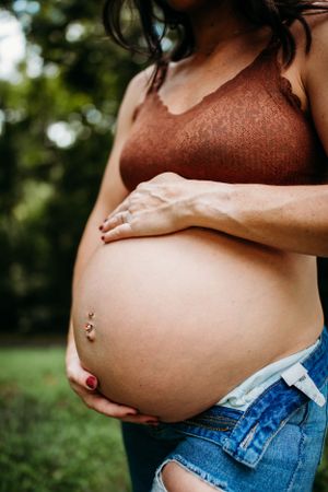 Maternity woman holding belly for maternity photoshoot. Captured by Maryland Photographer Mallory Bramlett.