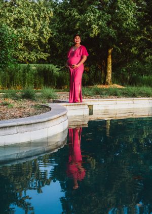 maternity woman standing by water with reflection for maternity pictures. Captured by Maryland maternity Photographer Mallory Bramlett.