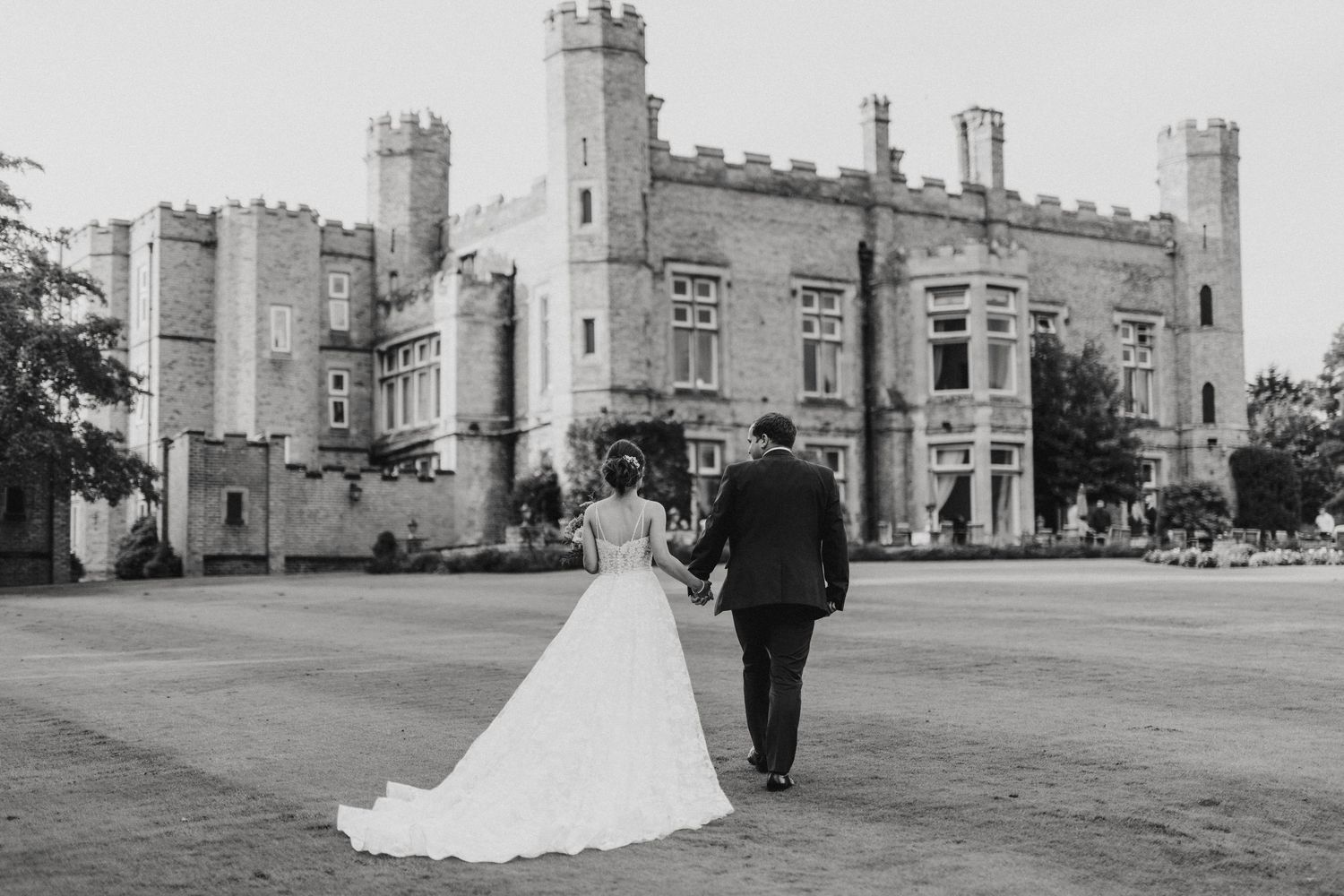 Wedding couple walk towards historic stone castle on the grounds of Cave Castle - taken by Grimsby photographer.