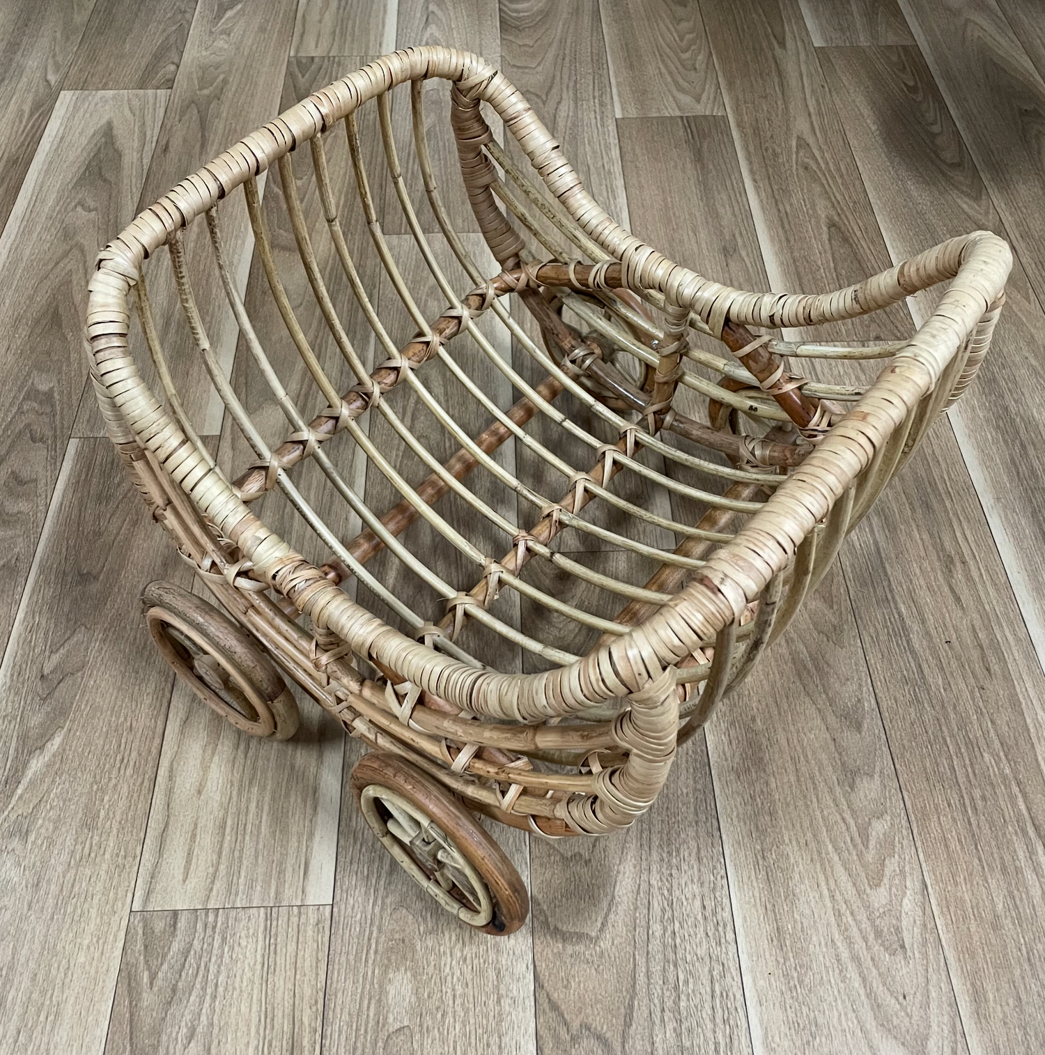 Curved wicker basket displayed in various positions on hardwood flooring.