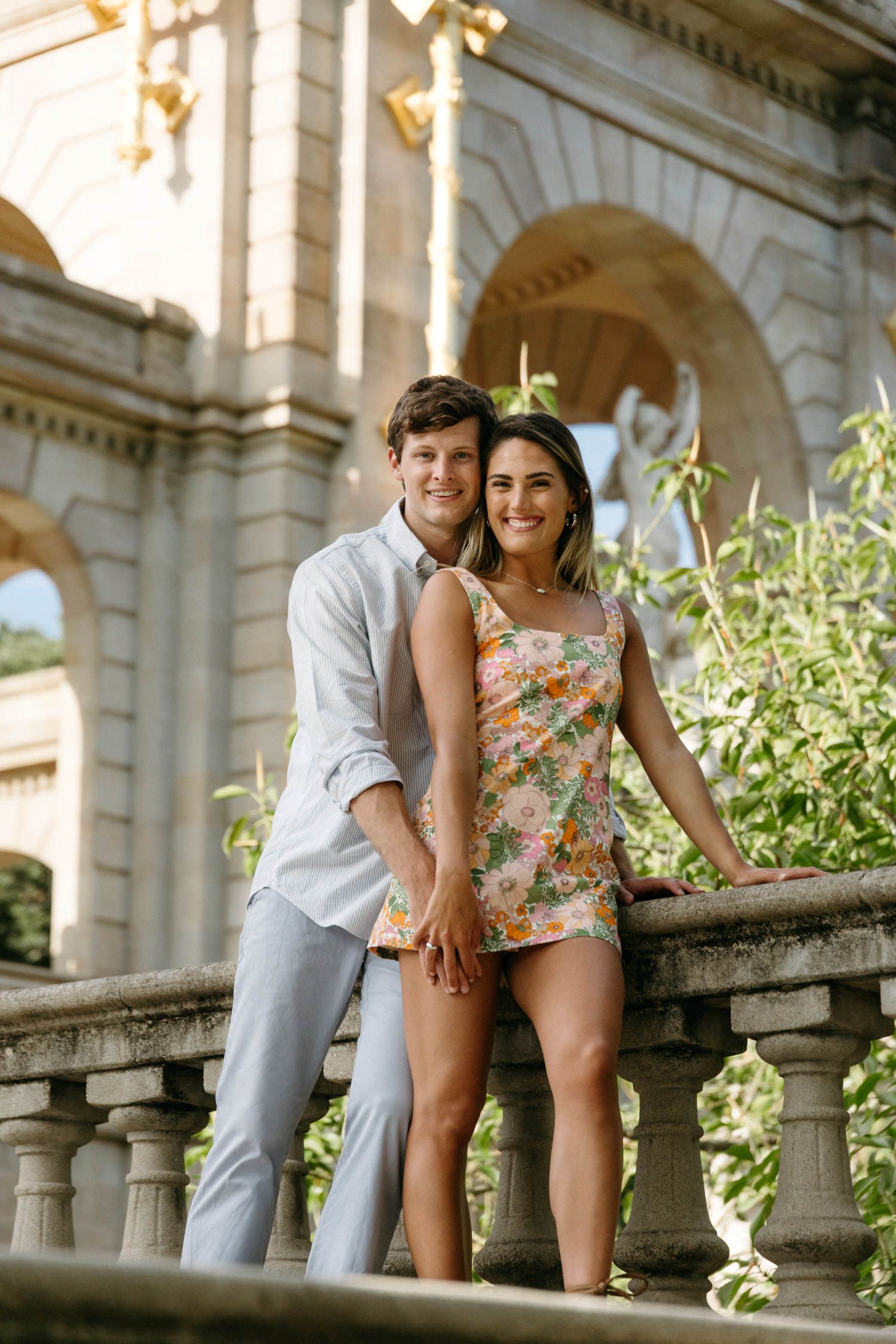 Playful moments captured along classical stone balustrade with ornate architecture.