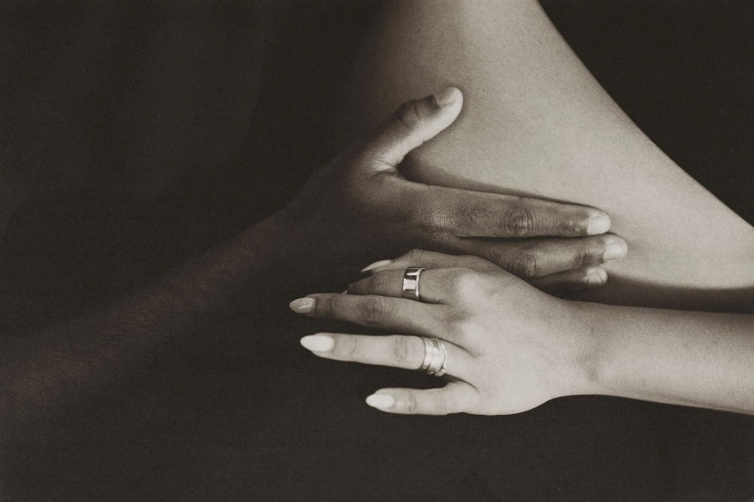 Black and white maternity photo - partner kissing baby bump indoors