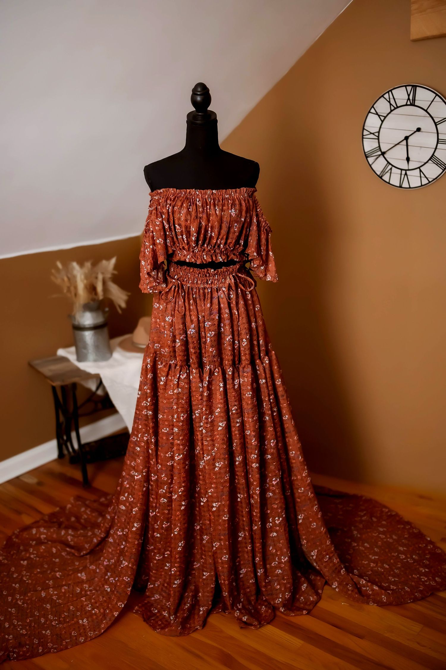 A vintage-style rust colored maxi dress with puff sleeves and tiered skirt displayed on a black dress form mannequin.