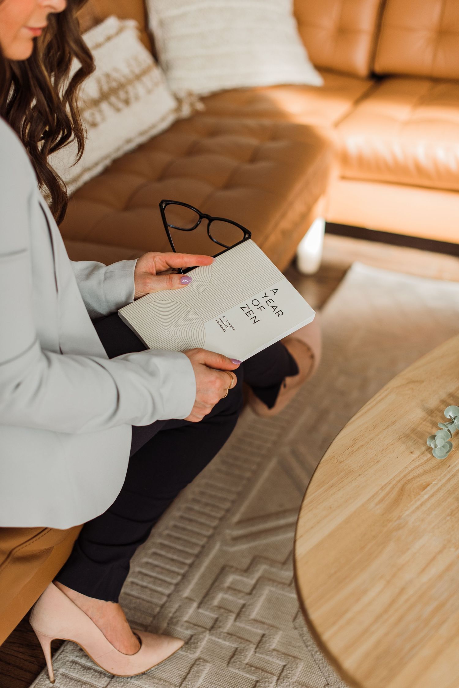 Someone writes in a notebook at a wooden desk with warm lighting creating a cozy study atmosphere.