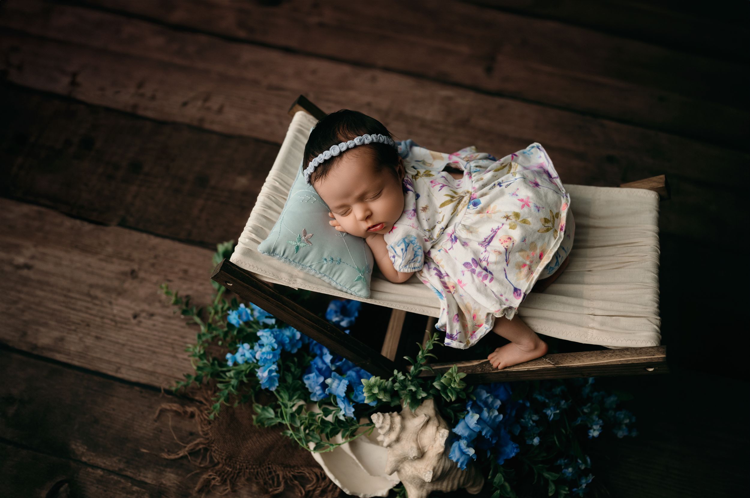 A person rests against an aged wooden floor with blue flowers and an open antique book beside them.
