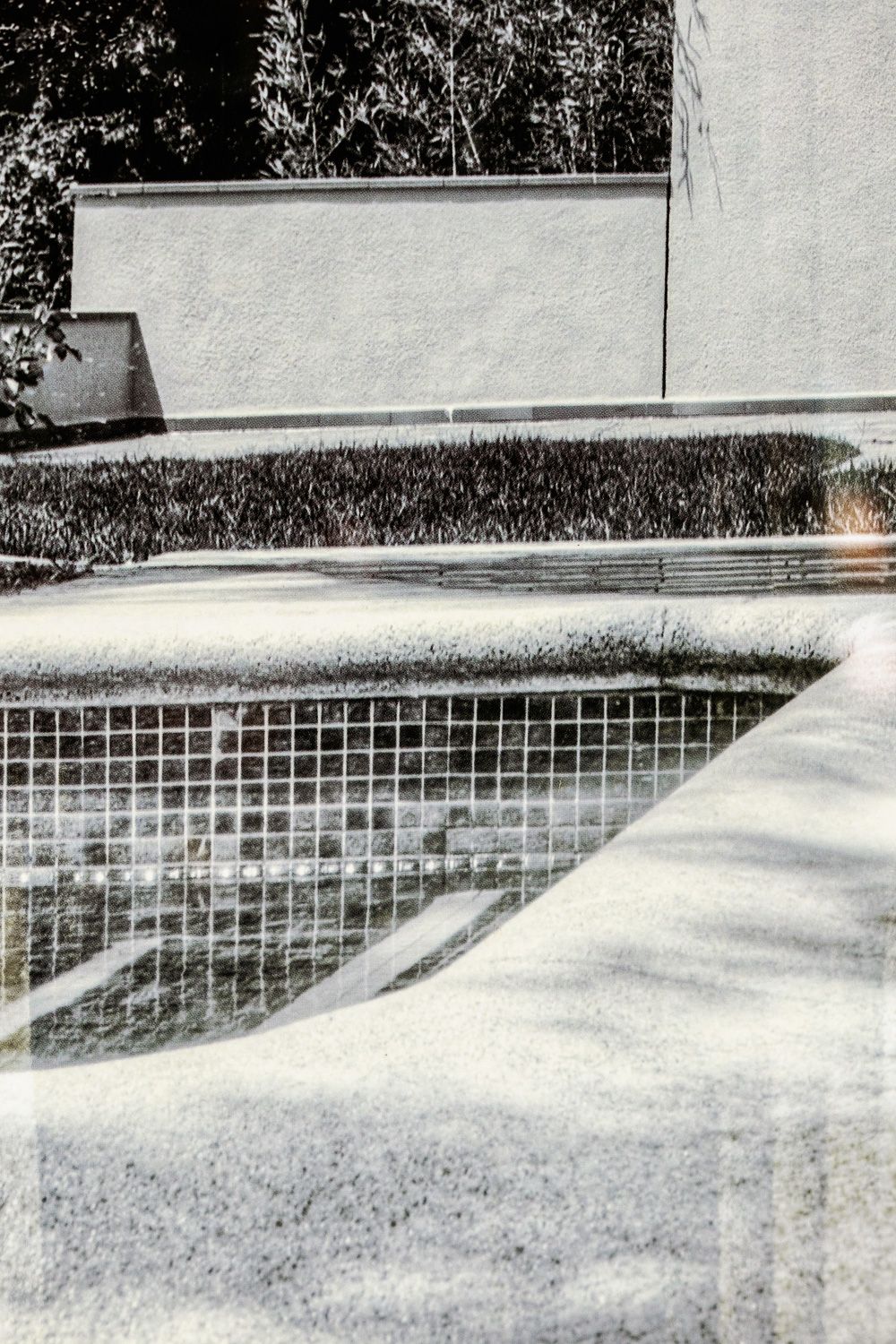 A panoramic view of an empty swimming pool transition showing detailed tiling and steps, captured in monochromatic style.
