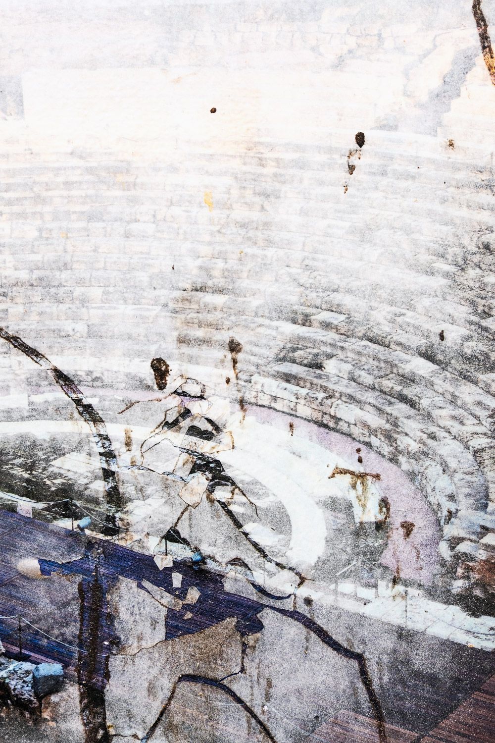 Abstract painted wall texture showing cracked layers of white and gray with dark shadows creating an ethereal pattern.