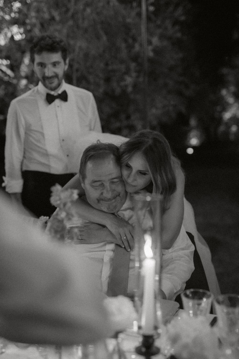 Intimate candlelit dinner scene at wedding reception in black and white photography.