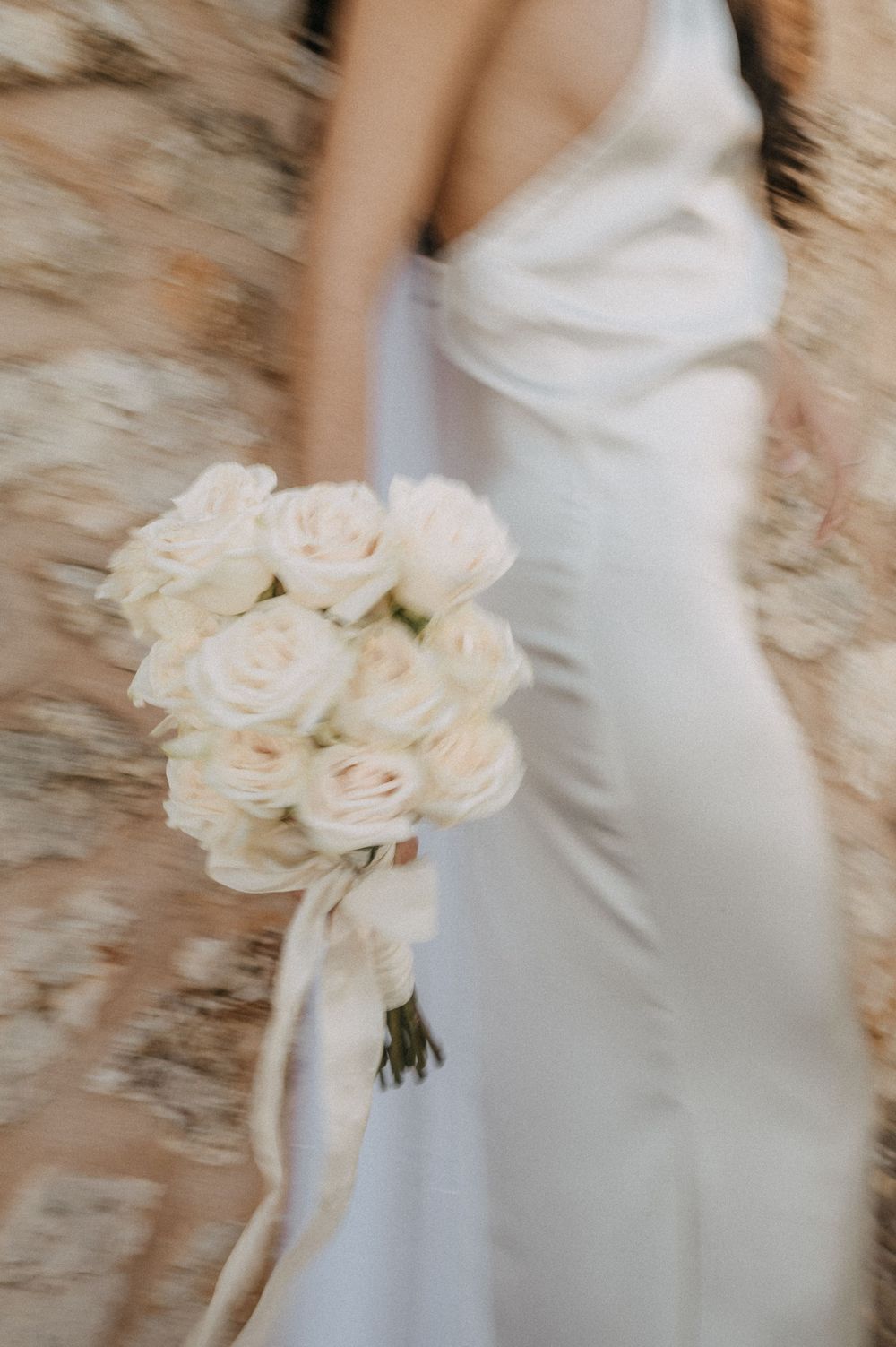 Elegant white roses bouquet with flowing wedding dress in motion.
