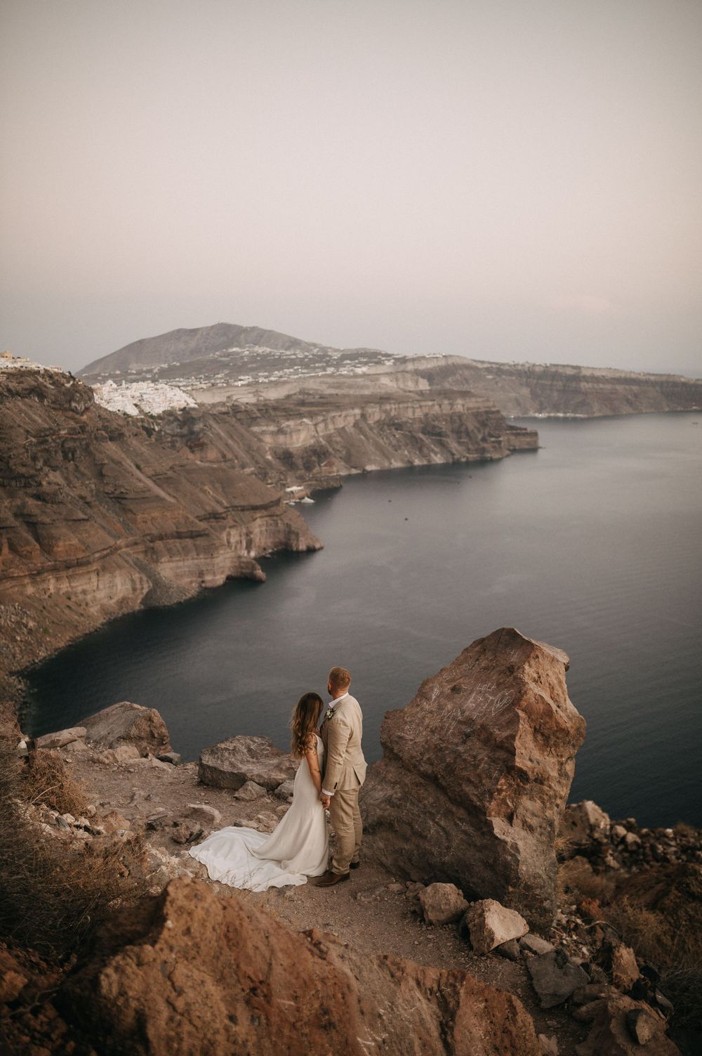 Dramatic coastal wedding photo with cliff views and scenic Mediterranean landscape. Santorini Wedding Photography