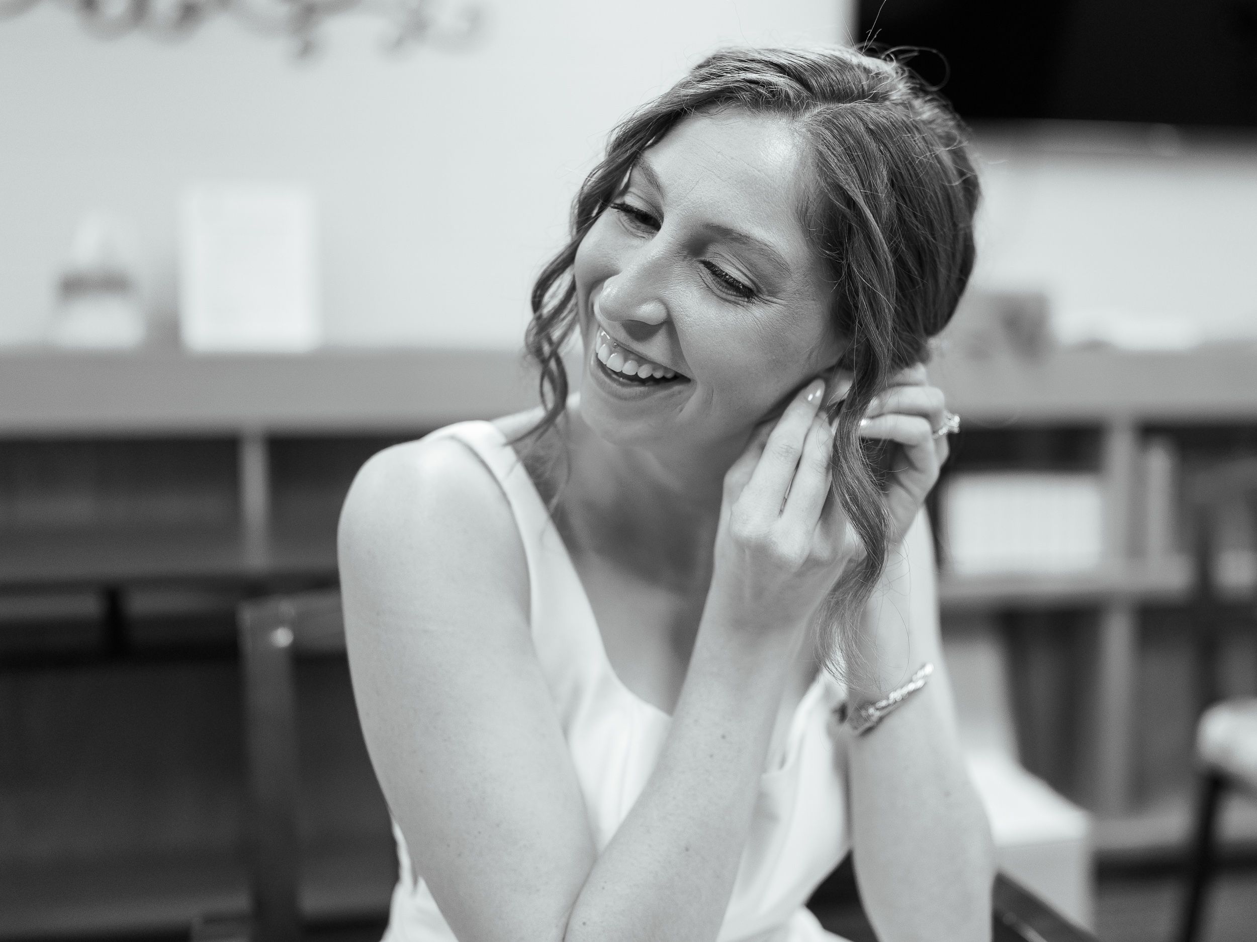 A joyful moment captured in a black and white photograph showing someone laughing while wearing a white sleeveless top.