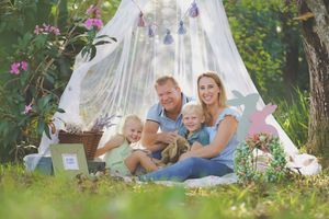 A family Easter portrait outdoors under a netted tent with easter decorations and a family smiling at the camera