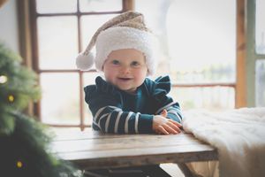 A chubby baby smiling in a Chriist mas had and jersey