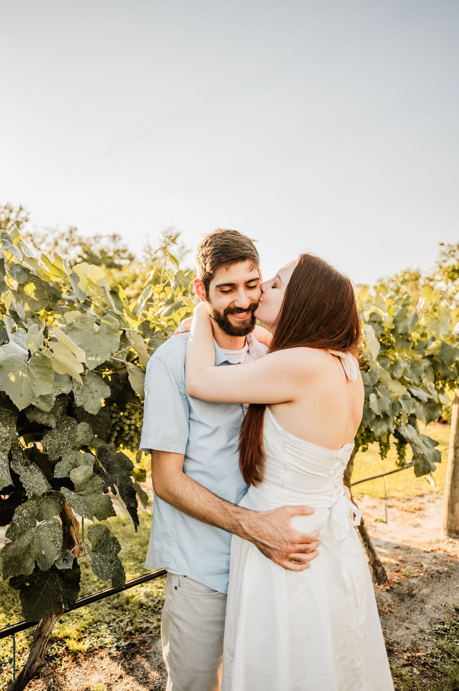 Romantic moment in sunlit vineyard between affectionate couple.