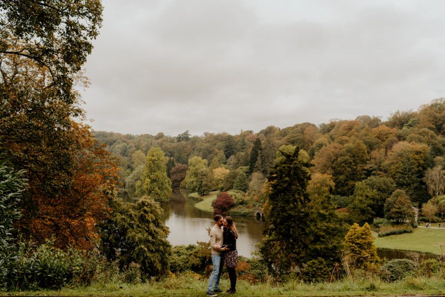 Autumn trees and rolling hills create a dramatic landscape backdrop on an overcast day.