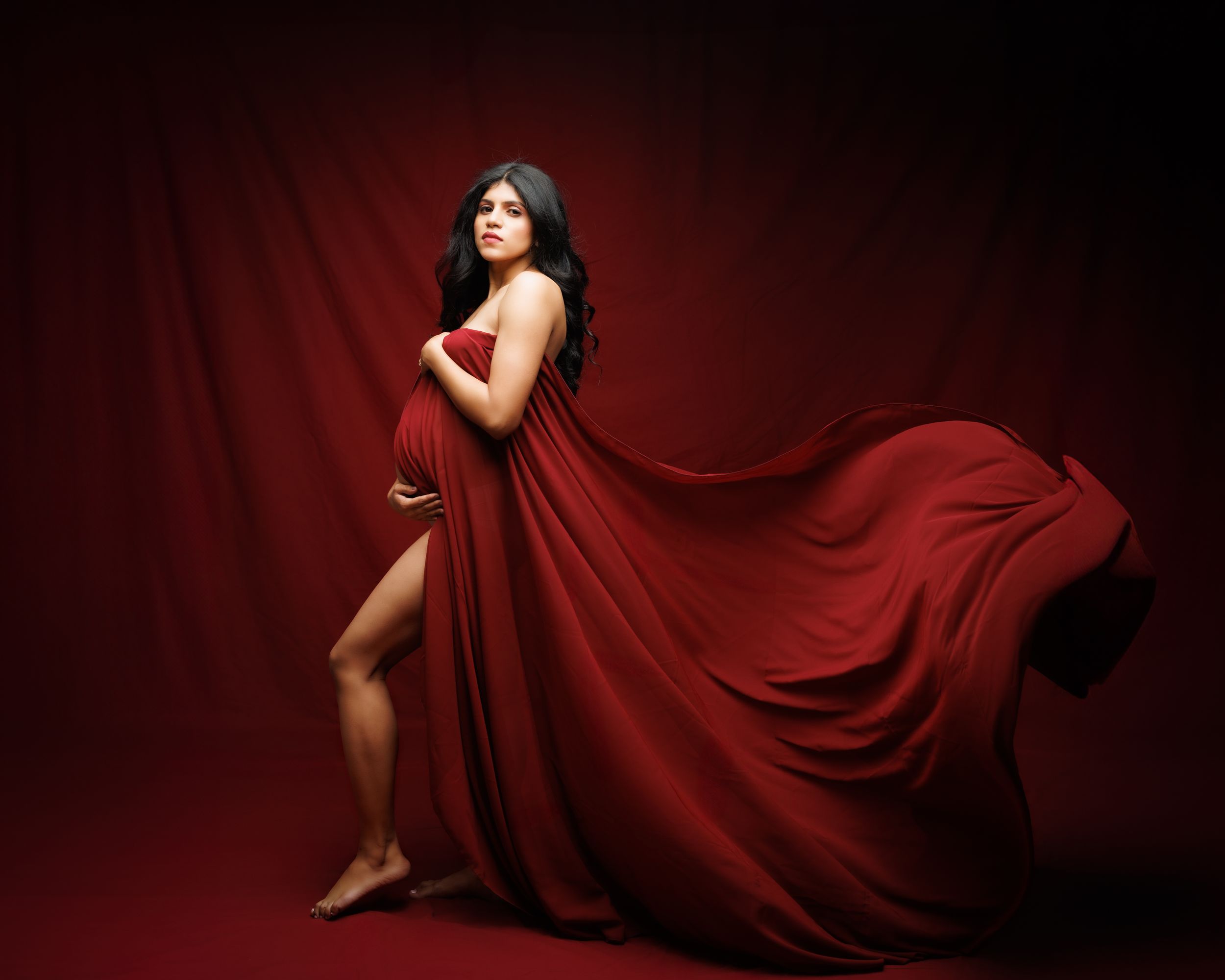 A flowing red dress fabric creates a repeating pattern against a dramatic dark background in an artistic series.