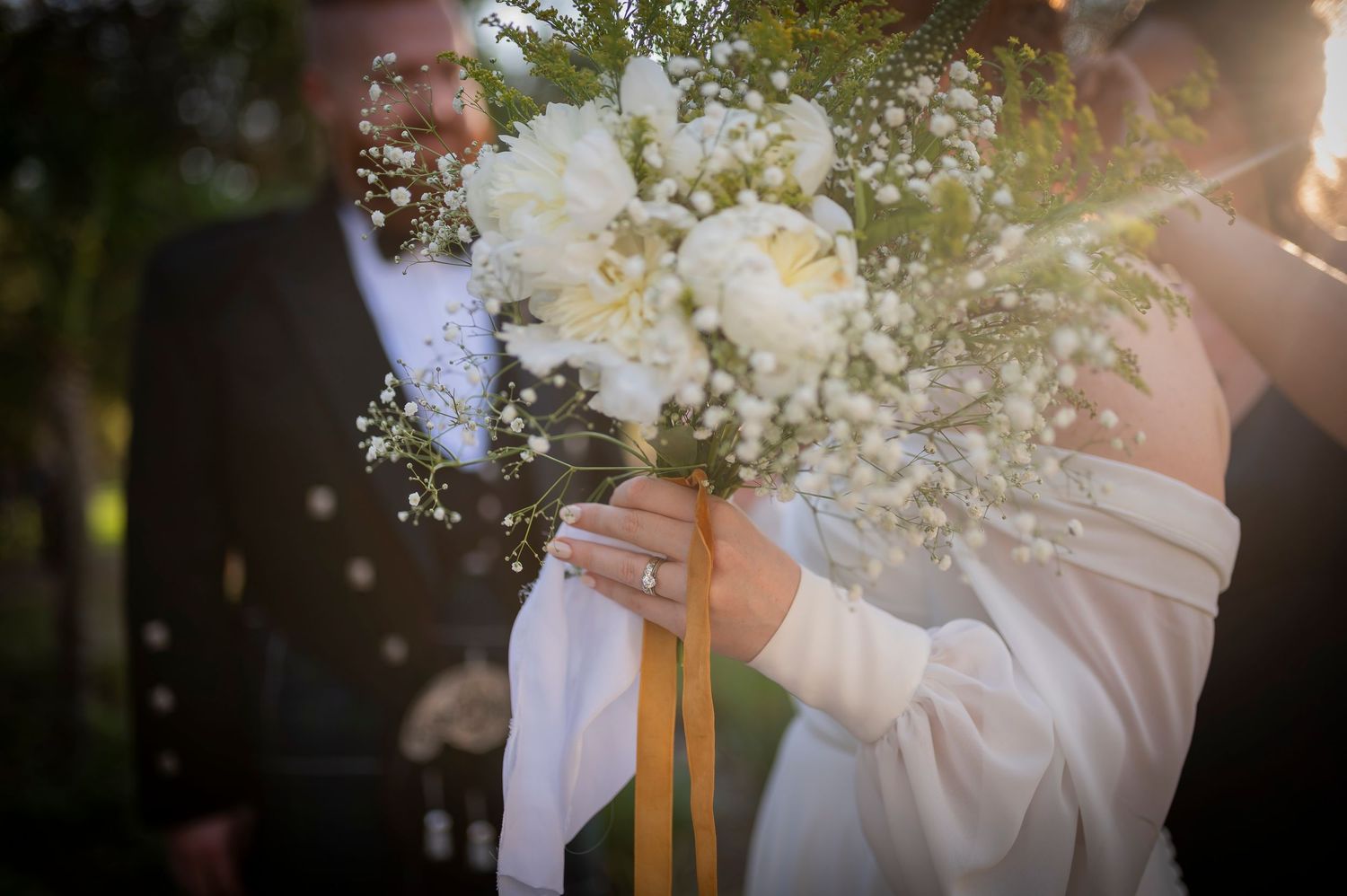An ethereal white wedding bouquet with baby's breath captured in soft natural light.