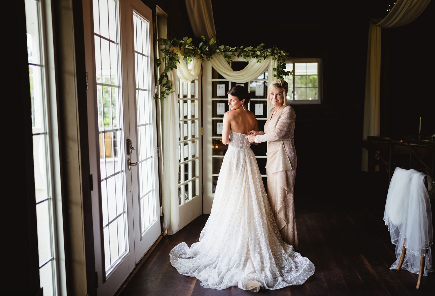 A row of elegant white wedding dresses hanging by windows in a bridal boutique, creating a romantic atmosphere.