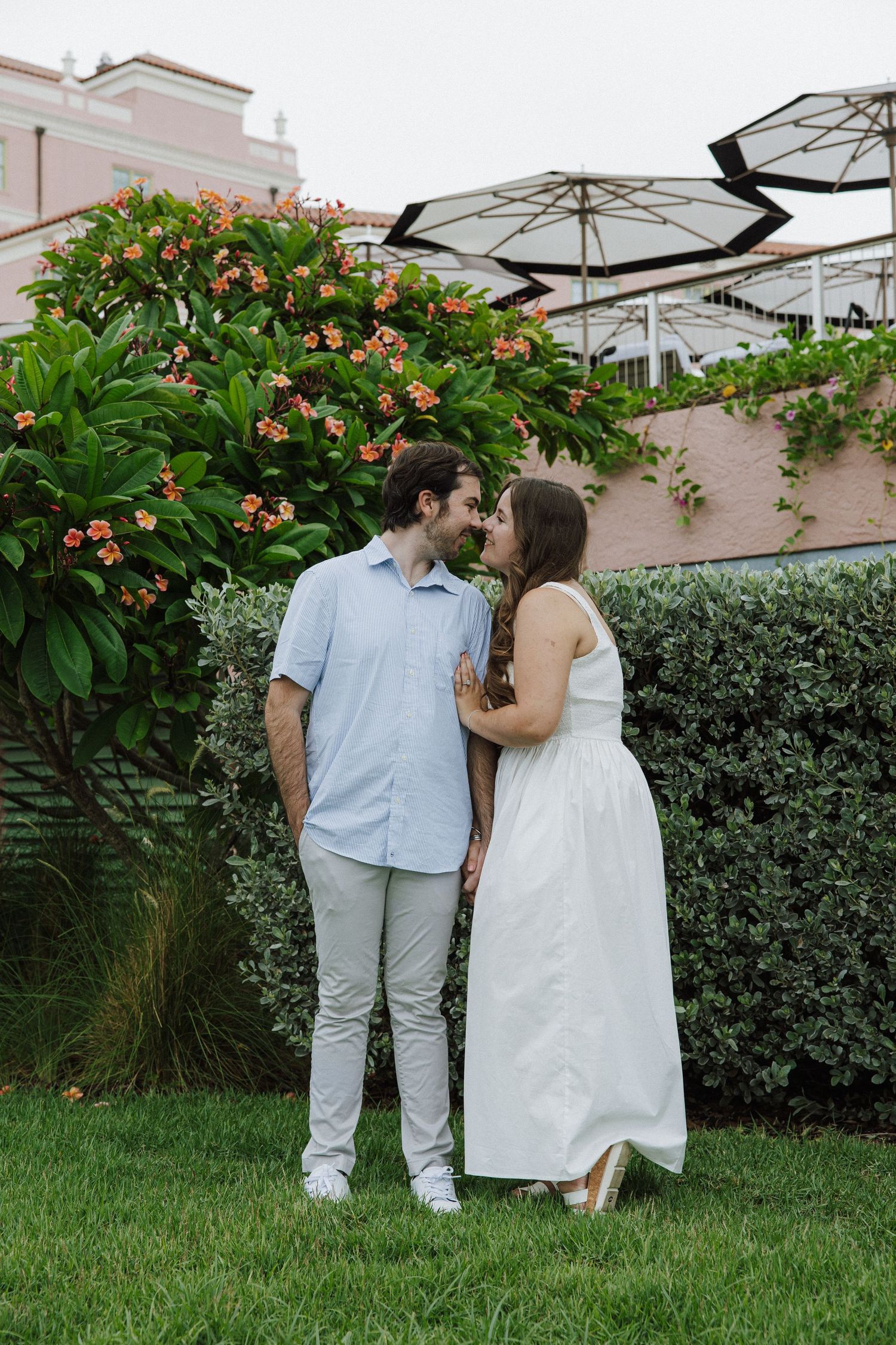 A couple shares three romantic moments on a green lawn with flowering bushes in the background.