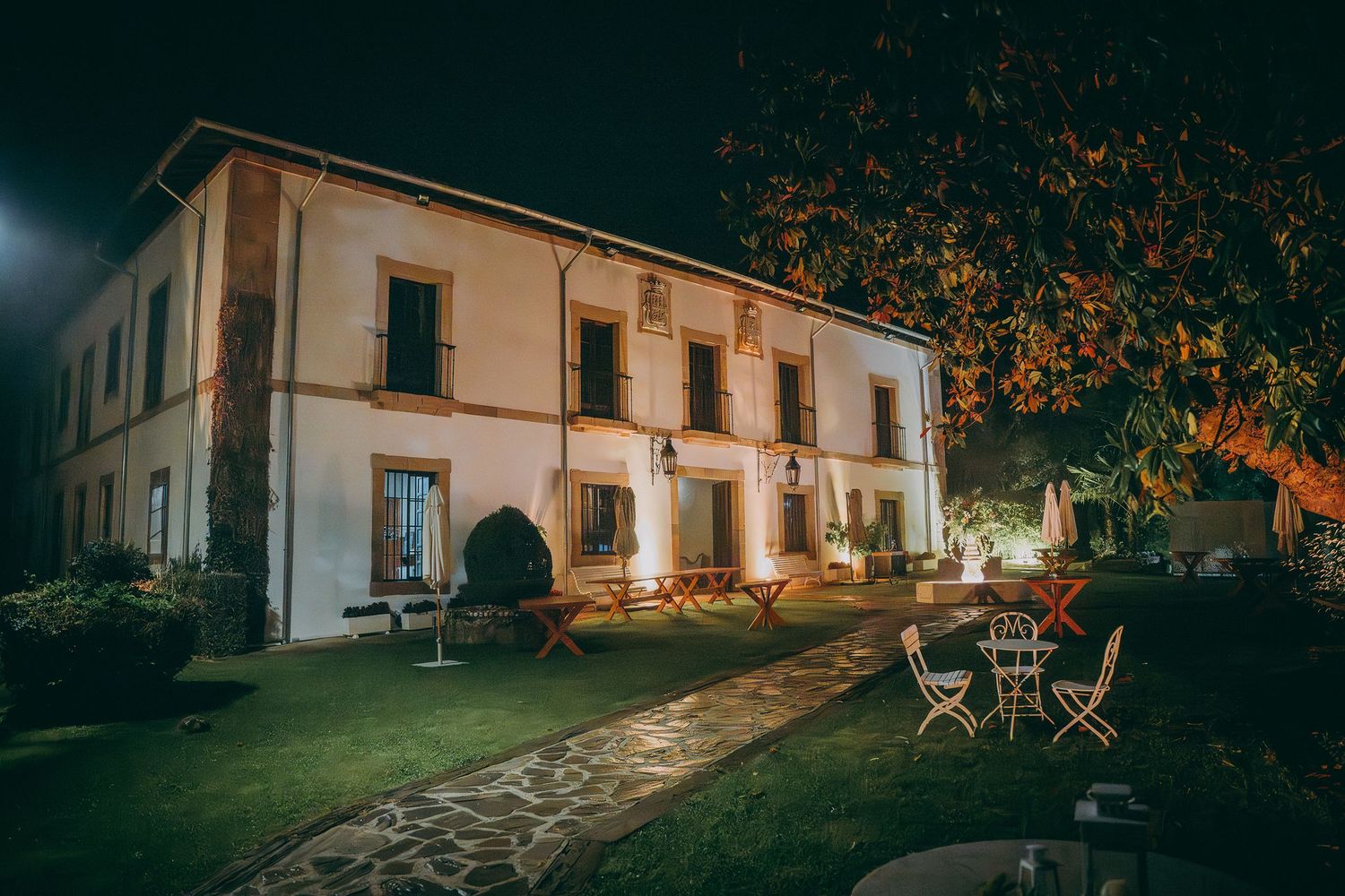 Palacio de Valdesoto iluminado de noche, sendero de piedra y jardines