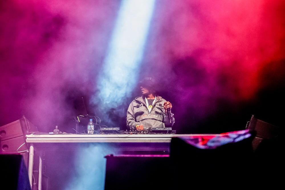 Concert stage with colorful purple and pink lighting effects creating a dramatic atmosphere during a live performance.