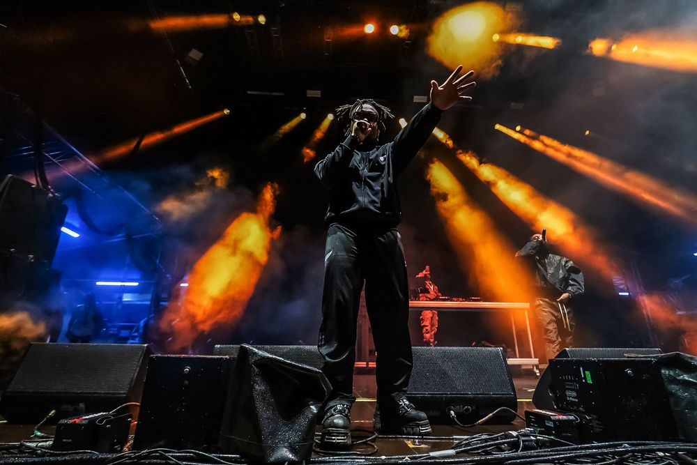 Performer silhouetted on stage with dramatic orange and blue lighting effects during a concert performance.