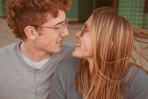 A couple shares a joyful moment together while laughing and looking at each other in warm lighting.