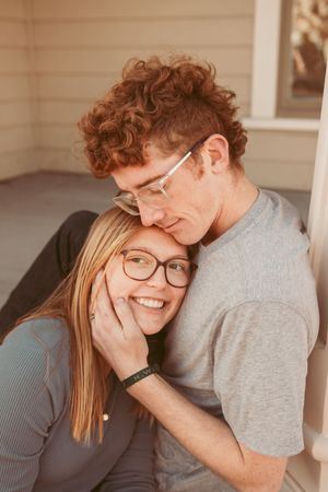 A couple sharing playful and intimate moments while sitting together on a porch.