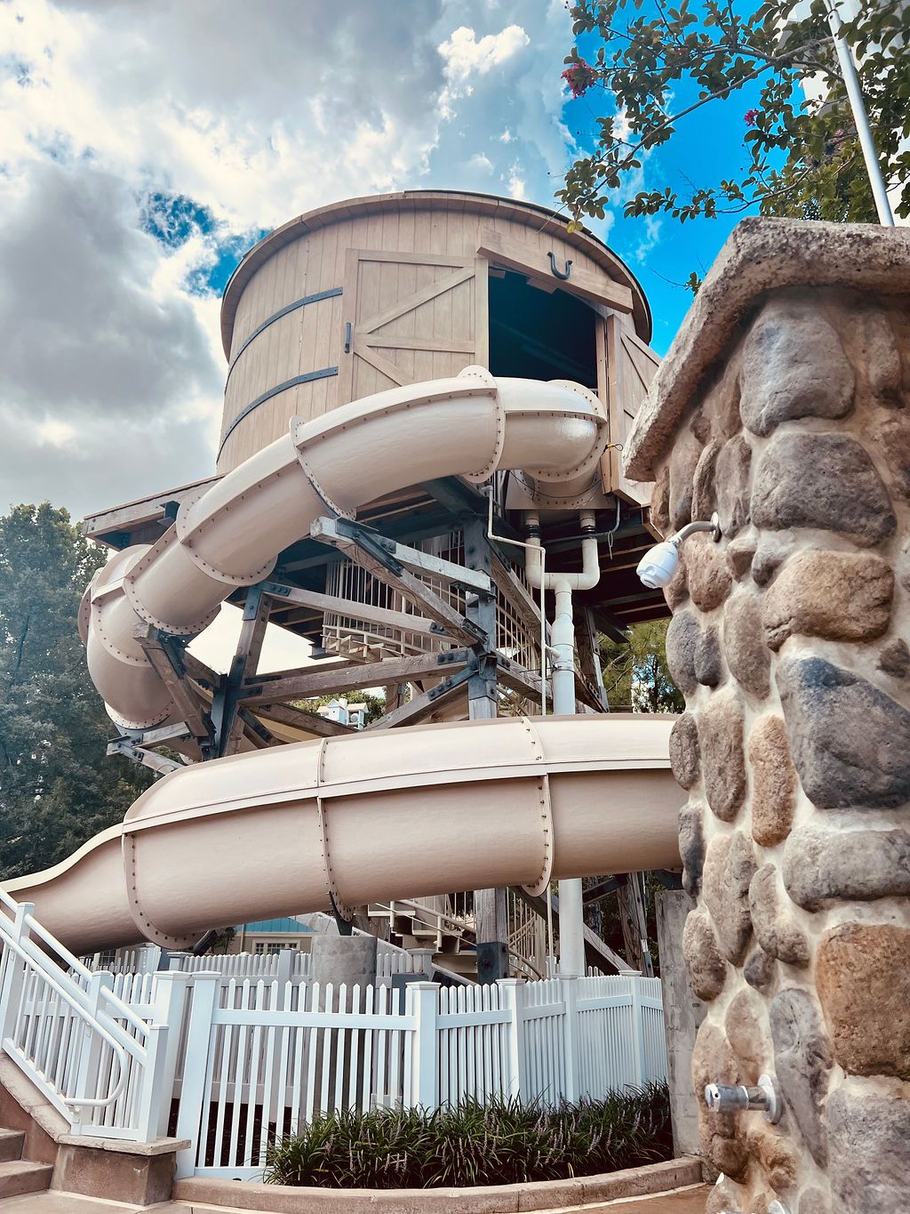 Spiral water slide with rock wall feature at Disney resort pool area.