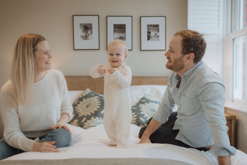 Family in coordinating white outfits shares tender moments during an indoor lifestyle photoshoot session.