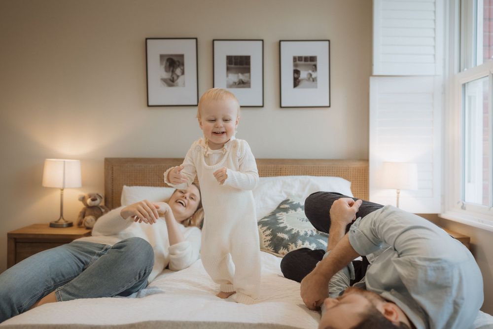 A sweet moment on a bed with natural light coming through the window, showcasing laughter and connection at home.