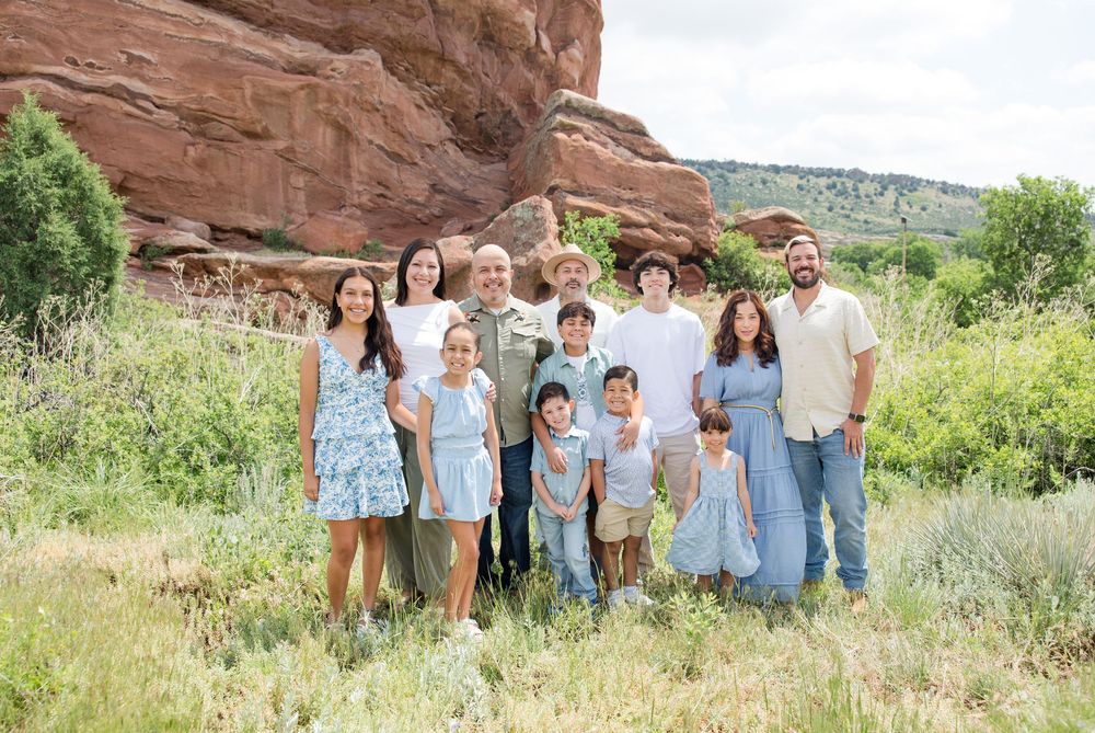 Group photo with scenic red rock formations and green vegetation in the background.