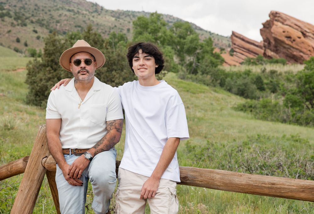 Family wearing coordinated blue and white outfits poses in front of mountain landscape.