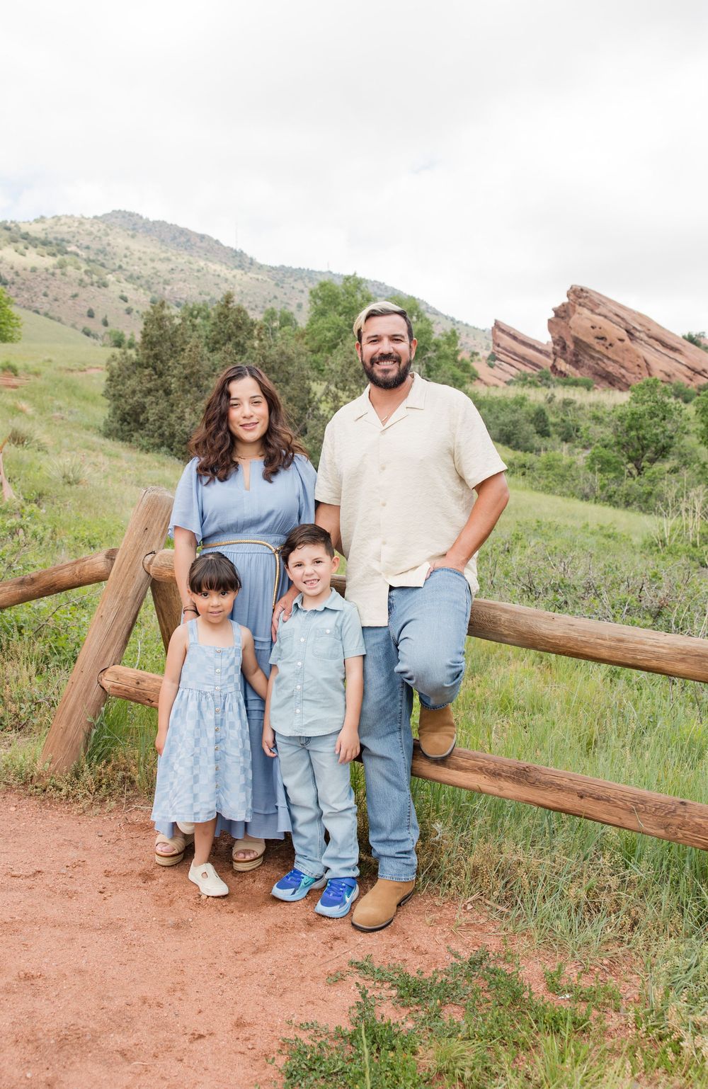 A family enjoying a scenic outdoor moment at Red Rocks Park in Colorado on a dirt trail with mountain views in the background.