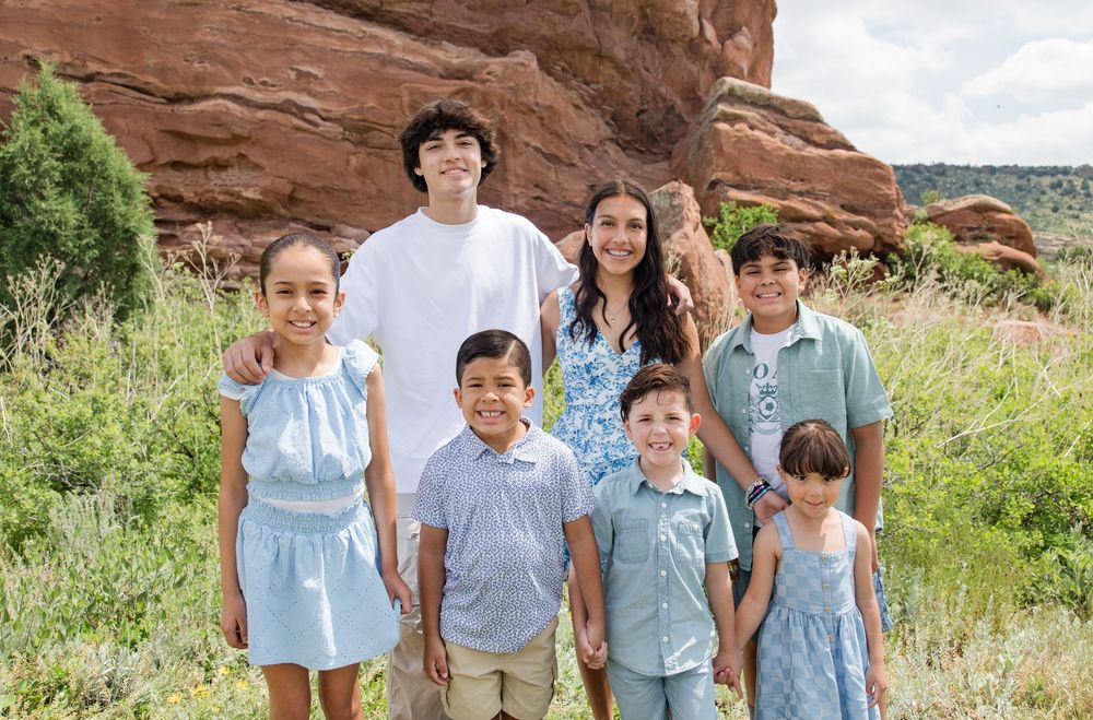 Family wearing coordinated blue and white outfits poses together against red rock formations in natural setting.