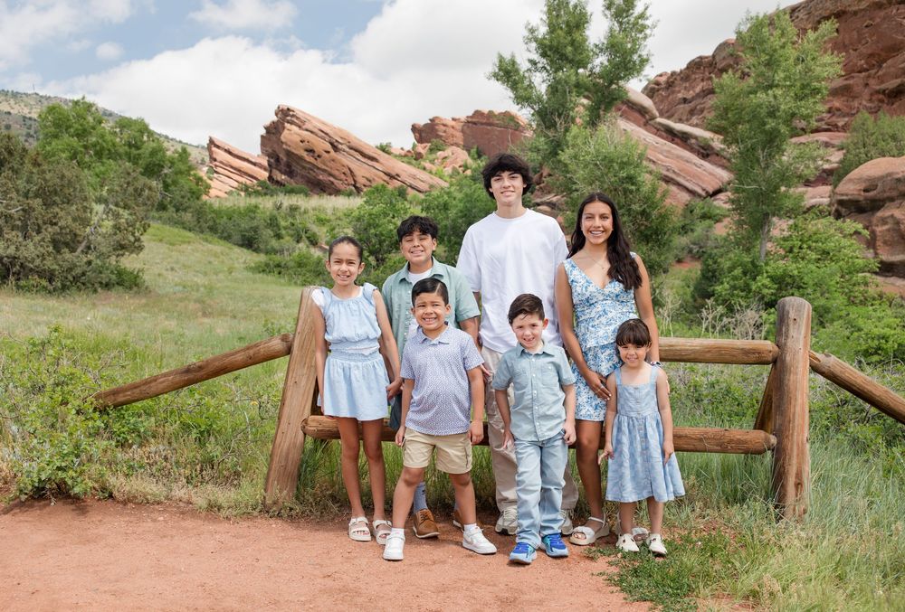 A group poses together on a hiking trail at Red Rocks with distinctive sandstone formations in the background.
