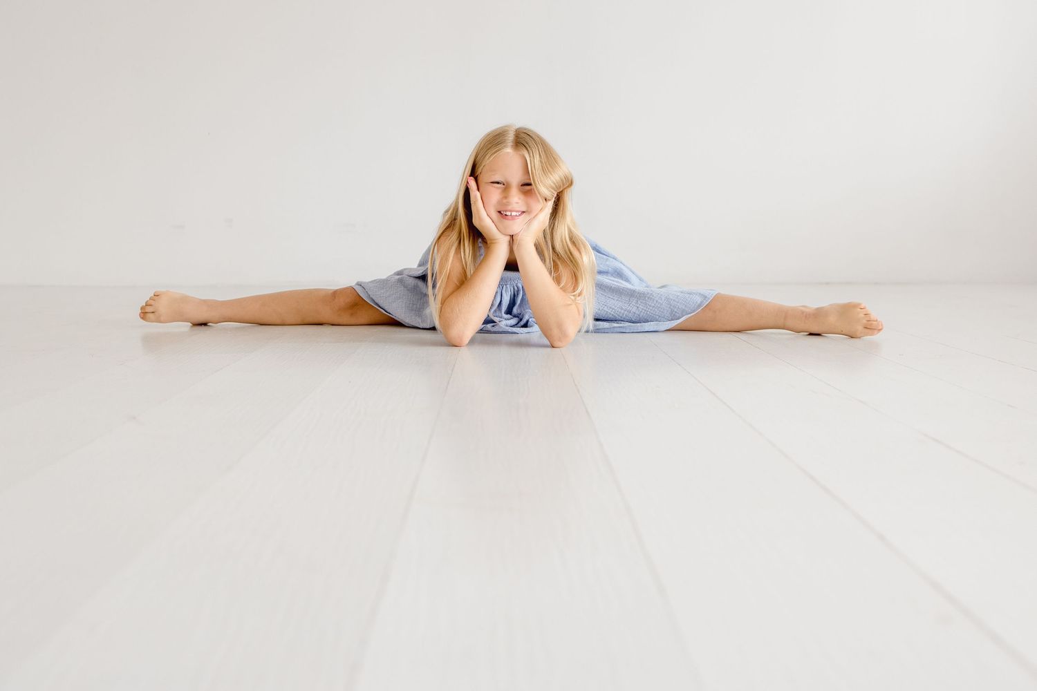 Casual studio portraits with subjects lying on white floor in coordinated blue and white outfits.