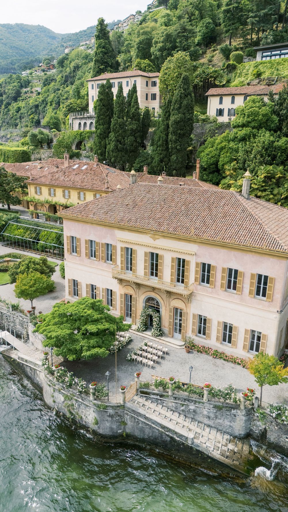 Aerial view of a luxurious villa wedding venue with white chairs set up for an outdoor ceremony.