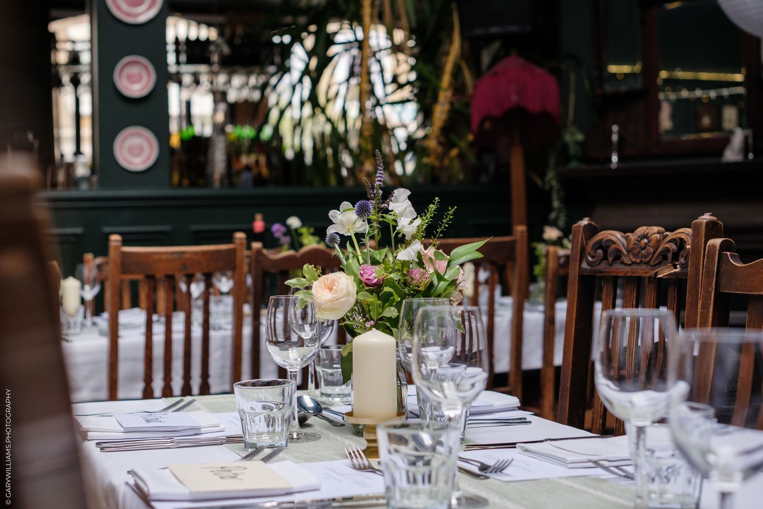 Tables set with elegant place settings and floral centerpieces in a rustic indoor venue.