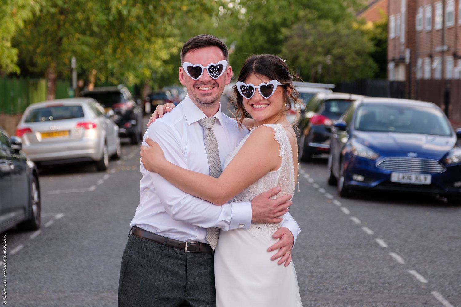 Couples enjoying a sunny outdoor gathering on a residential street lined with cars and trees.