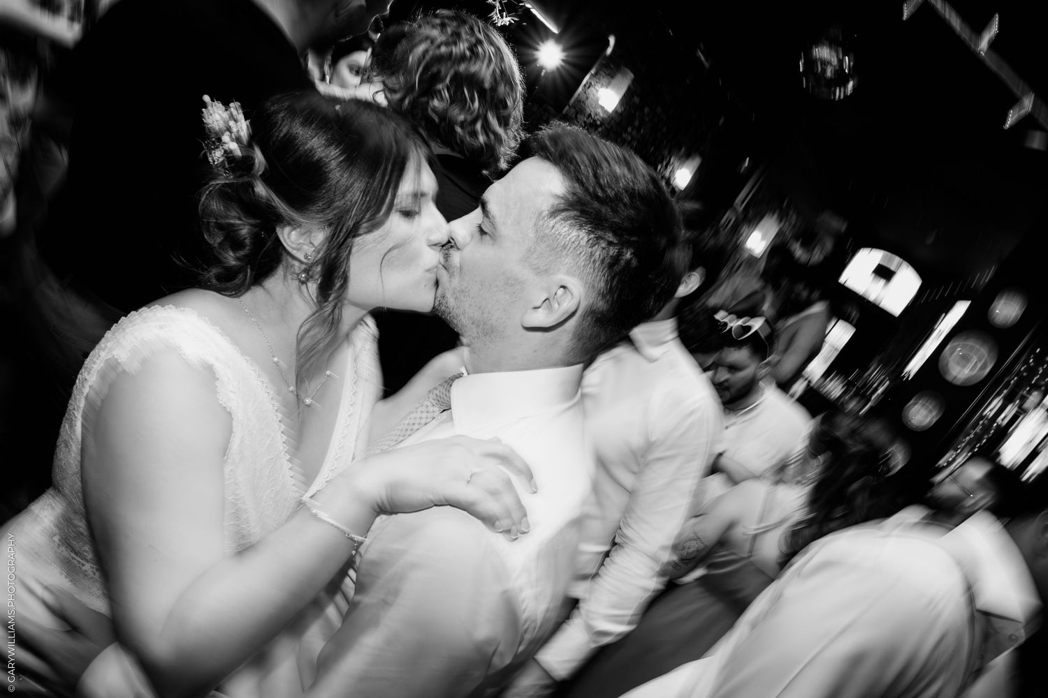 A black and white photo capturing guests dancing and celebrating at a lively party.