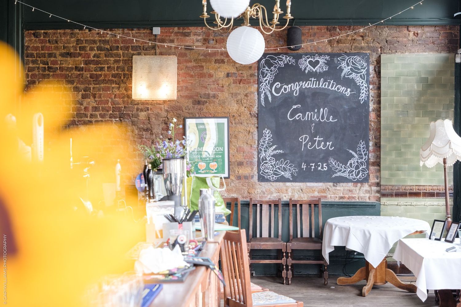 A rustic restaurant interior with exposed brick walls, chalkboard menu, and vintage decor creates a cozy dining atmosphere.