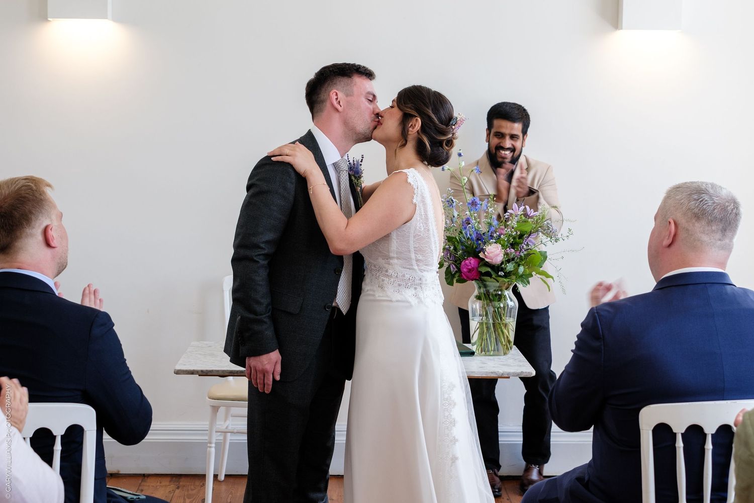 A series of wedding photos showing romantic moments and embraces between newlyweds at a bright indoor venue.
